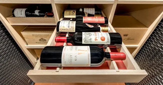 Assorted fine wine bottles stored in a wooden wine rack drawer, cellar setting